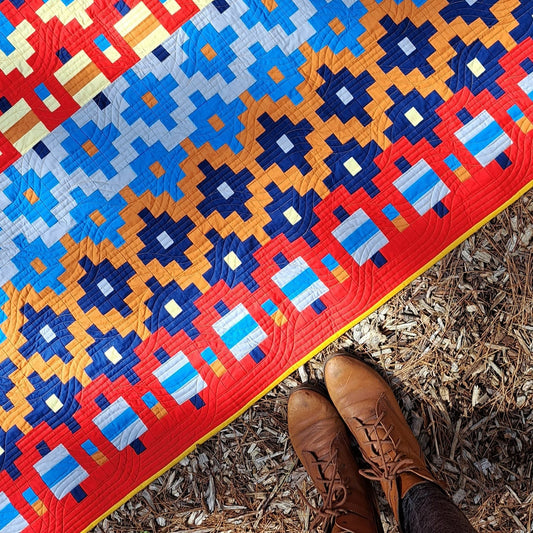 A close up of the Alentejana quilt laying on a forest floor.