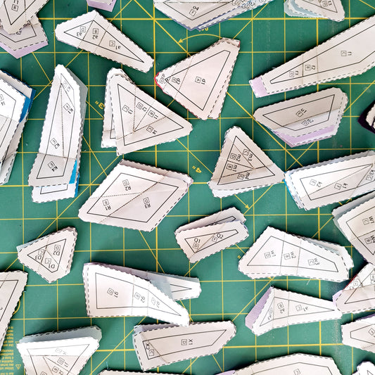 A variety of foundation paper pieced templates laying on a green cutting mat.