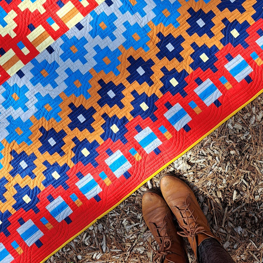 A close up of the Alentejana quilt laying on  a forest floor.