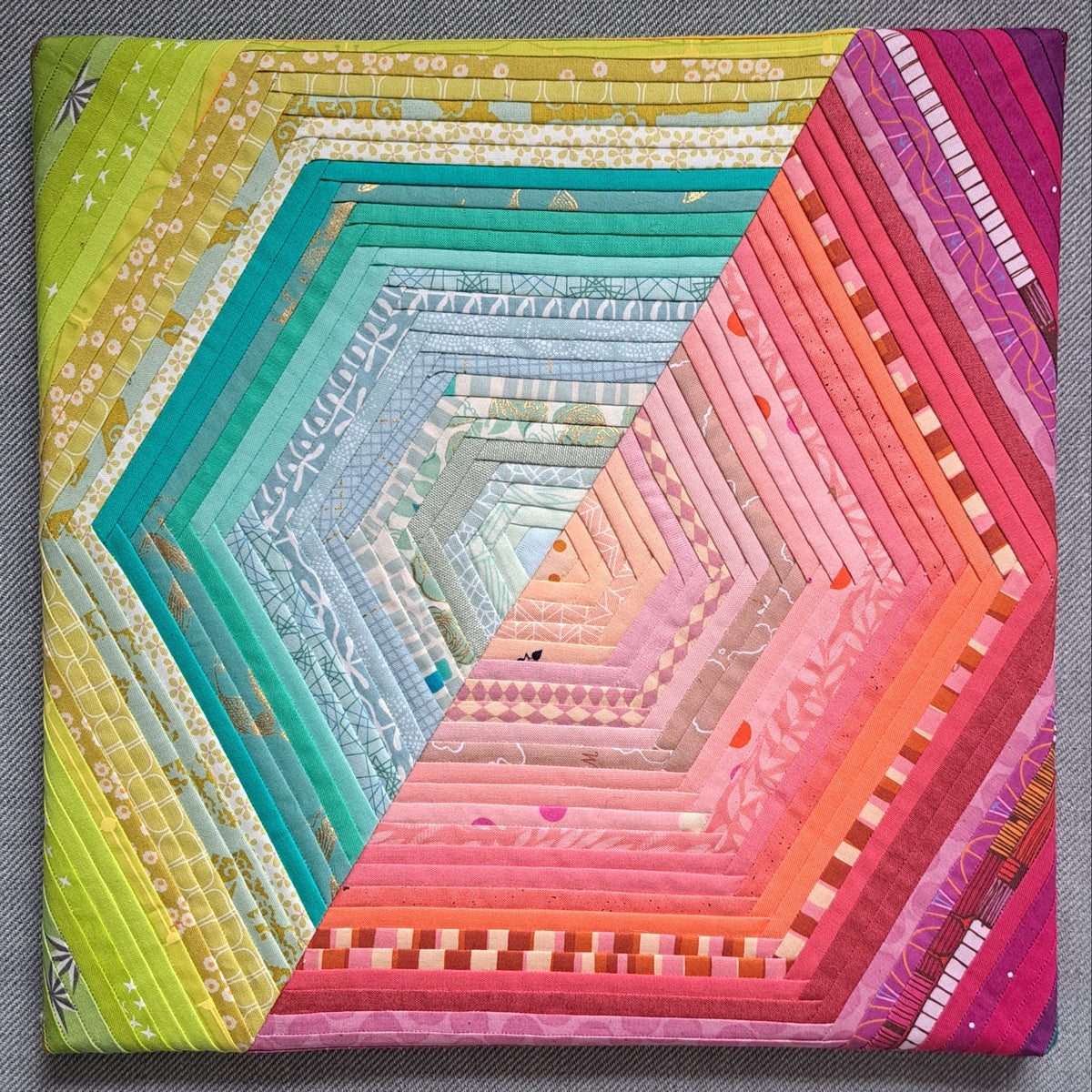 A hexagon made of two halves - one green and one pink - using quarter-inch foundation paper pieced sections. Mounted onto a canvas.